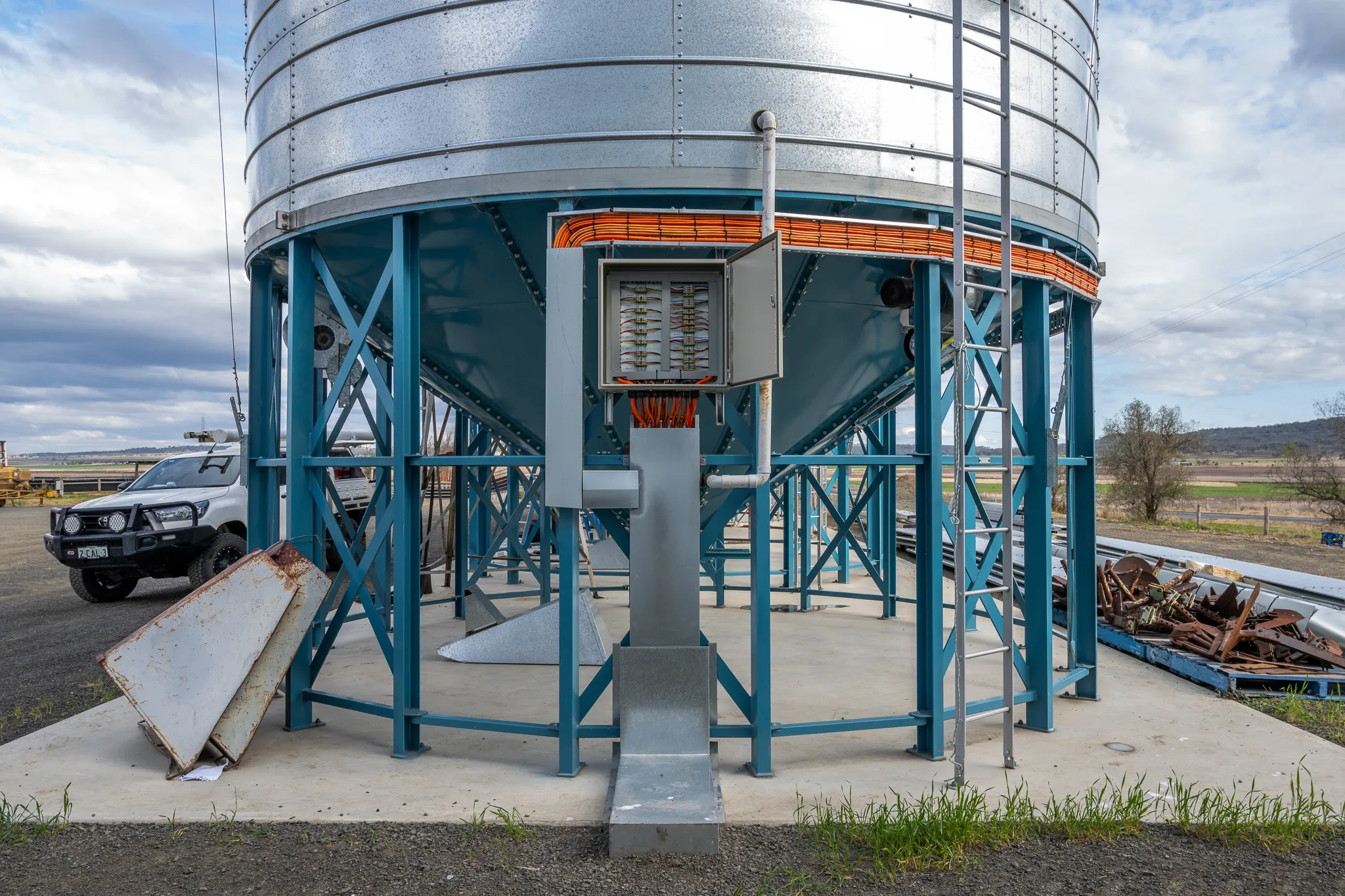 An open field-wiring enclosure and the orange sensor loom at the base of a grain silo.
