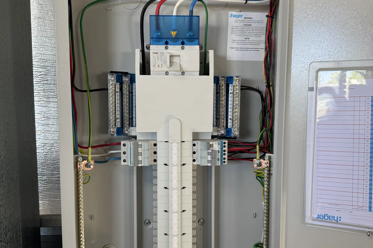 An open distribution board showing din-rail devices, colour-coded wiring and the circuit schedule.