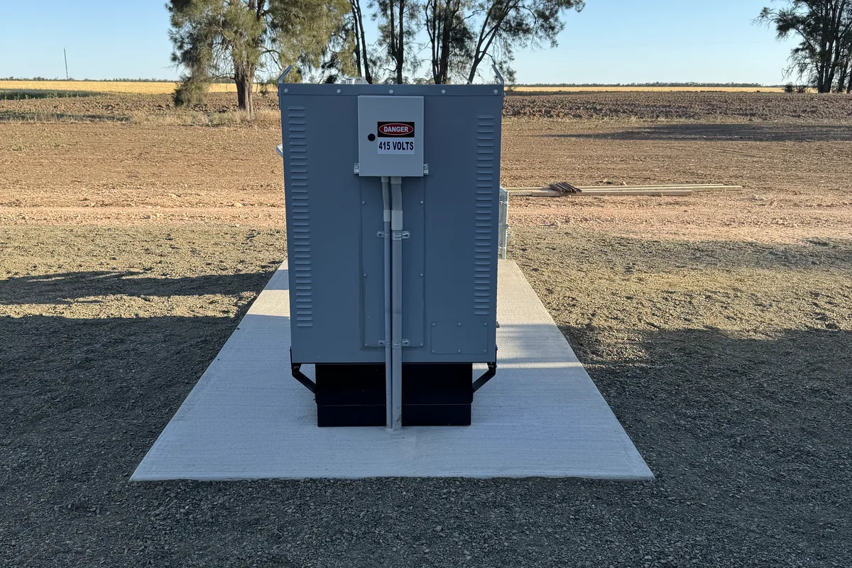 A generator set installed on a concrete pad in an open paddock.