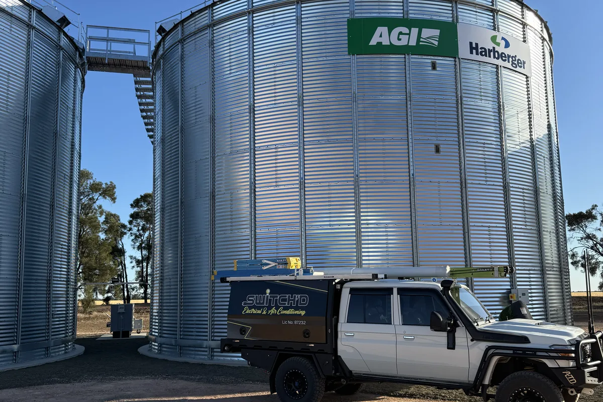 Switch'D ute parked alongside a row of AGI grain silos under deep blue sky.