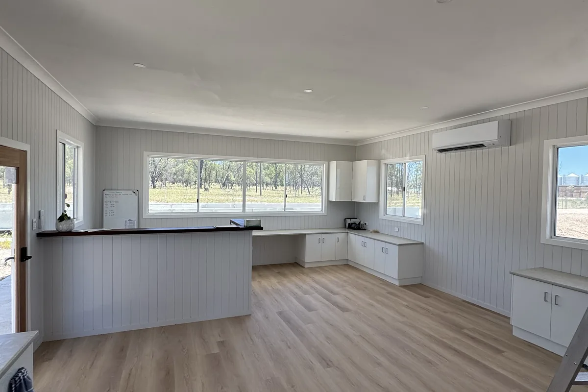 The open-plan kitchen and living area of a new home, lit and finished