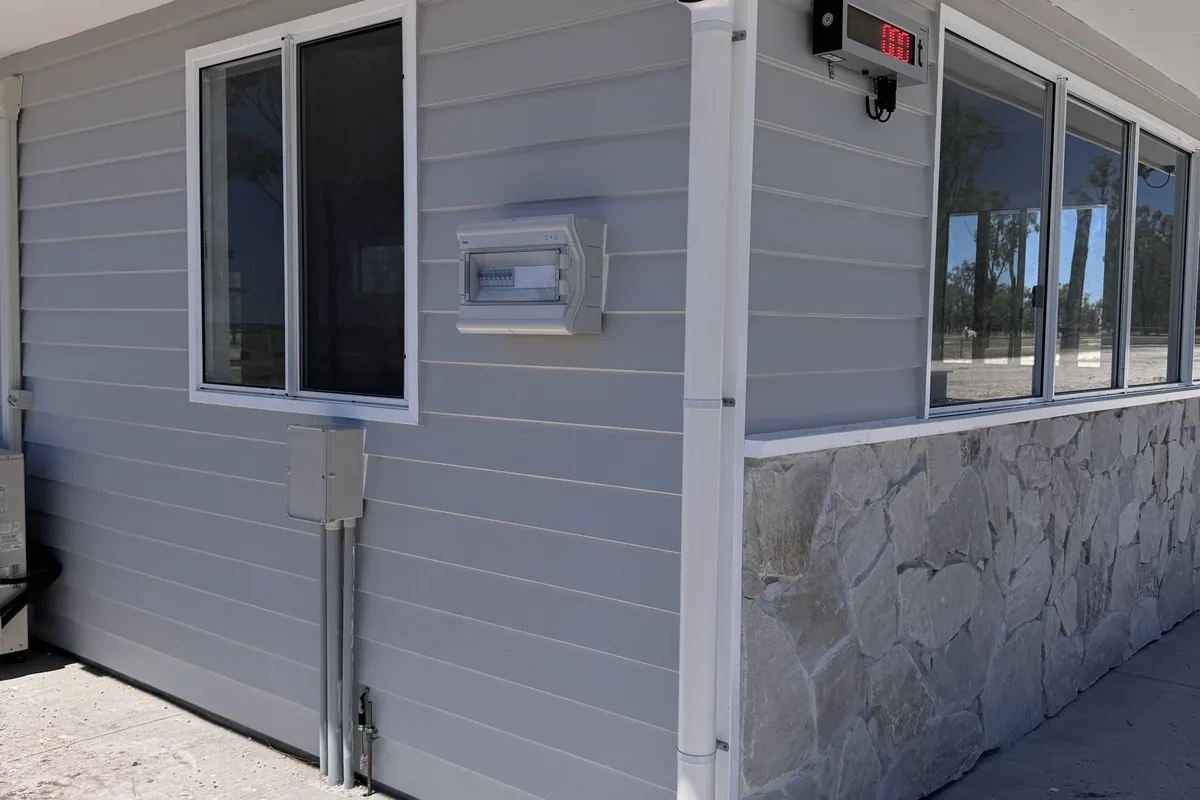 A split-system condenser and conduit run installed on the side of a new home