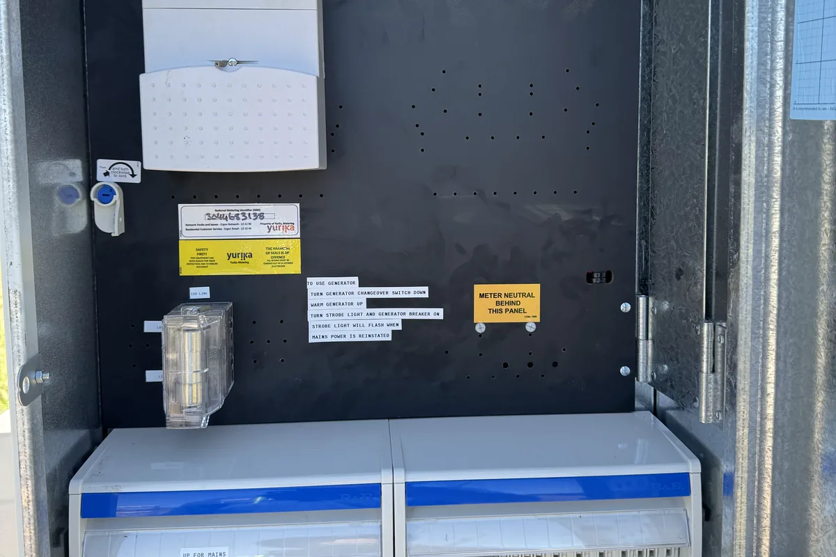 An open meter enclosure with the electricity meter, main switch and breaker bank.