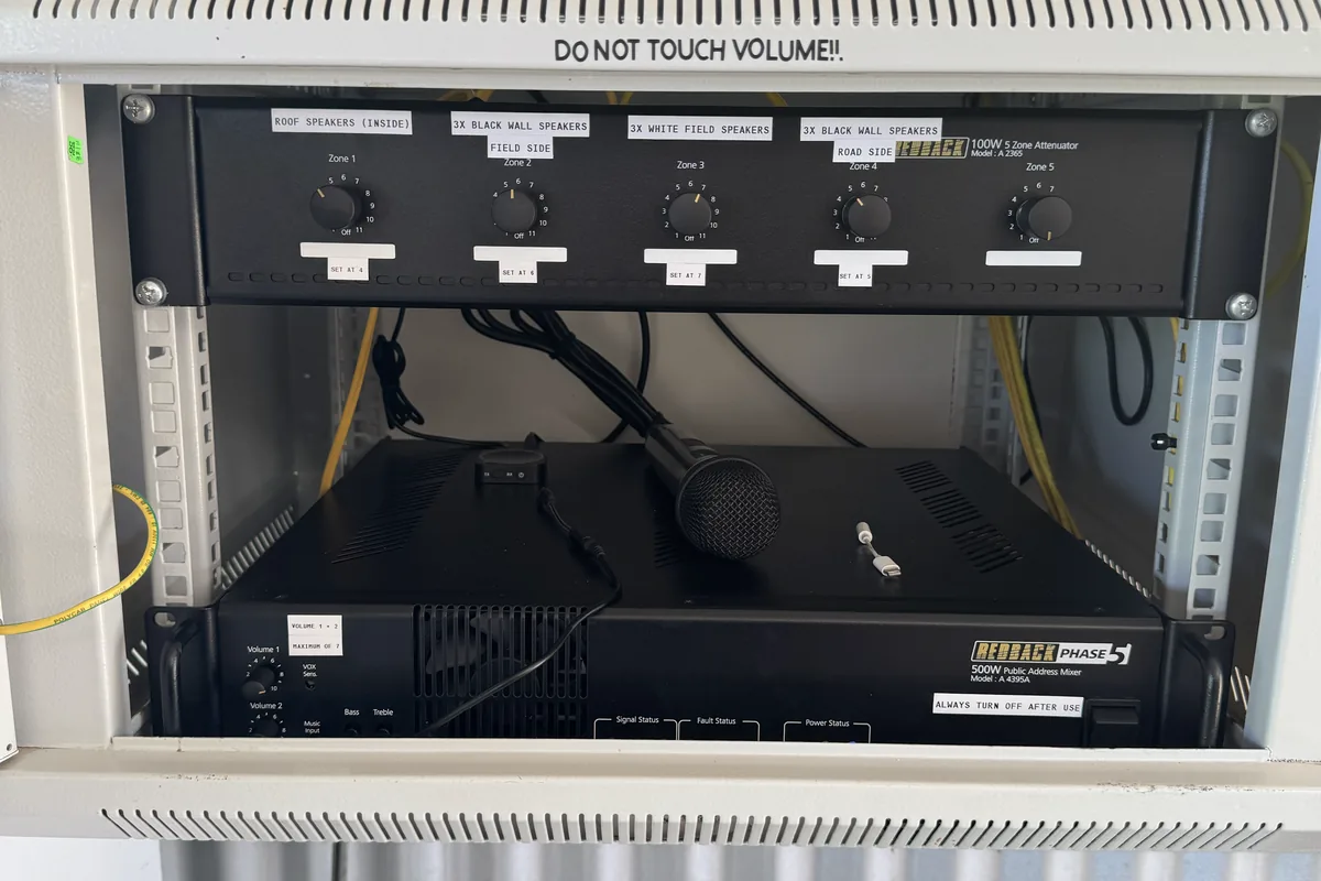 A rack-mounted PA amplifier and zone controls in a wall-mounted cabinet.