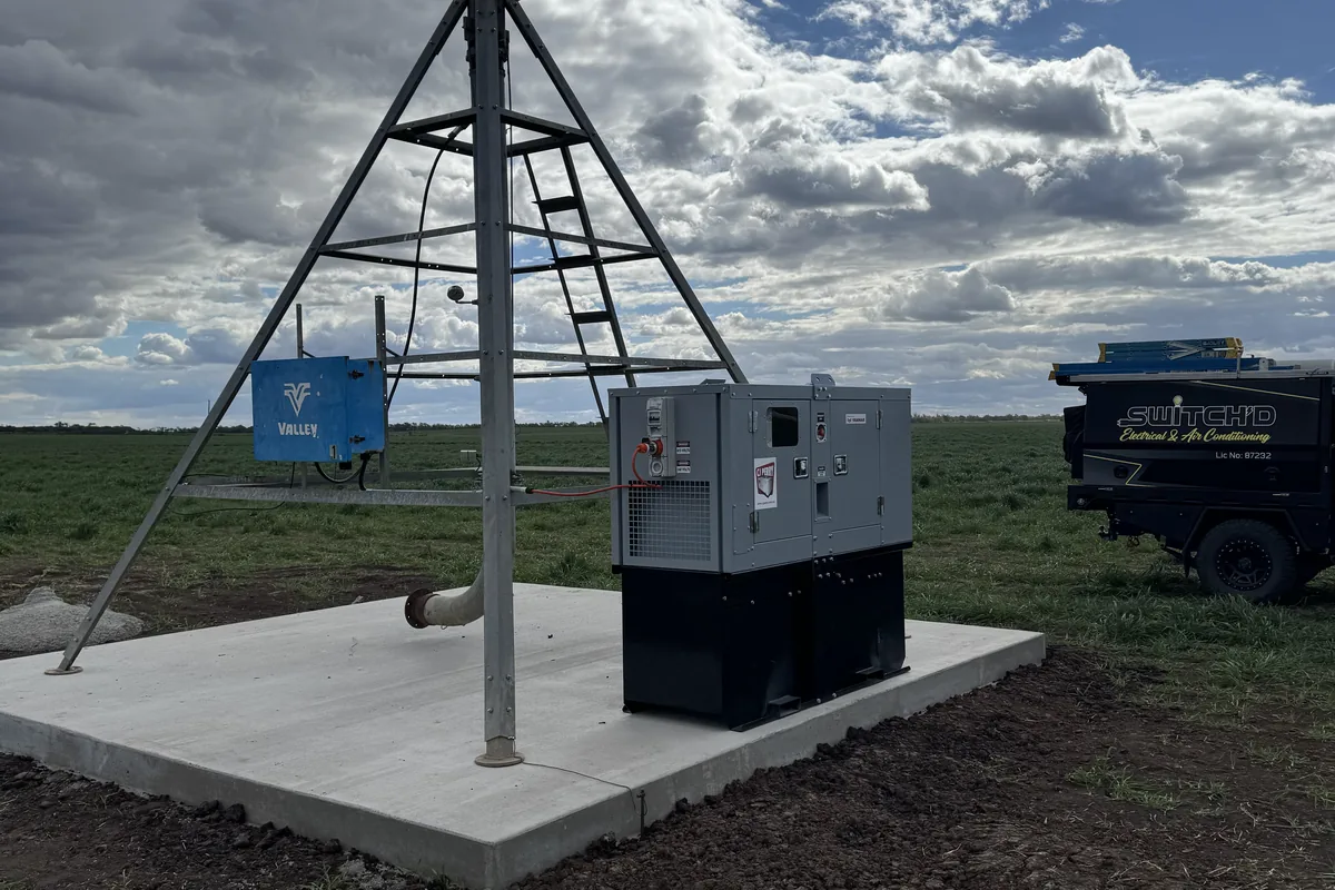 An irrigation pump cabinet on a concrete pad under a big cumulus sky.