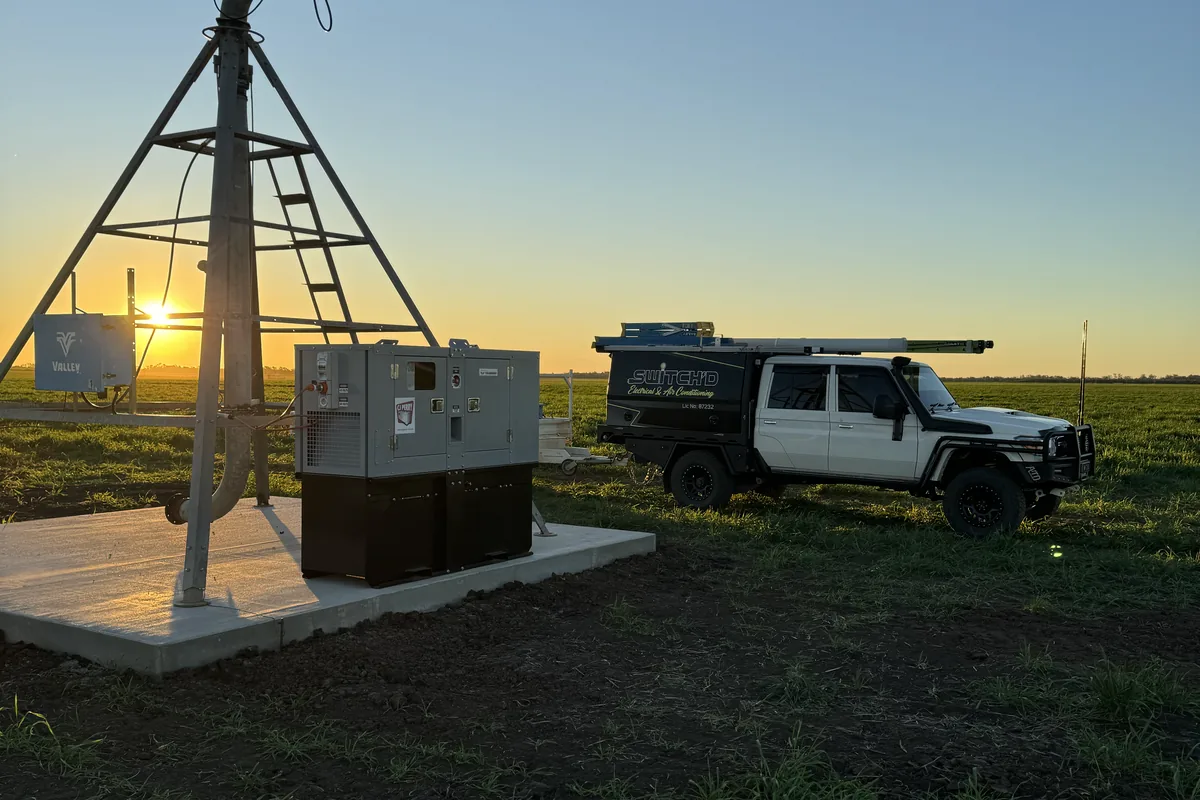 Centre-pivot tower, generator and control cabinet installed on a concrete pad at sunset
