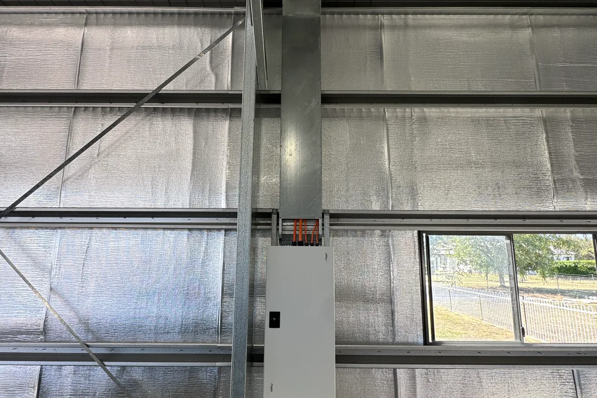 A panel board mounted to the frame inside an insulated shed.