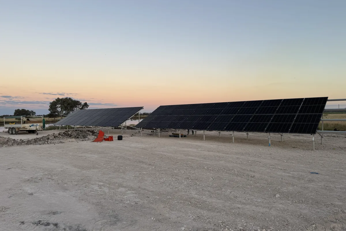 A ground-mounted solar array on a rural property at dusk